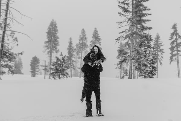 black and white photo of a Couple laughing in a snowy forest