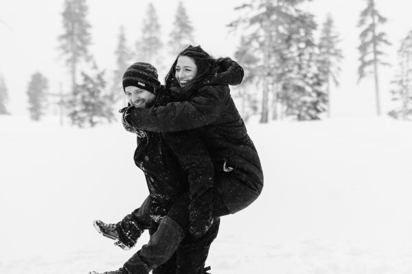 black and white photo of a Couple laughing in a snowy forest